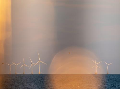 Wind turbines in the sea against sunset
