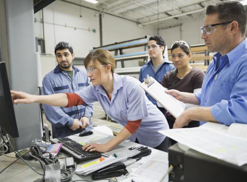 Team of people looking at a computer screen in a manufacturing environment