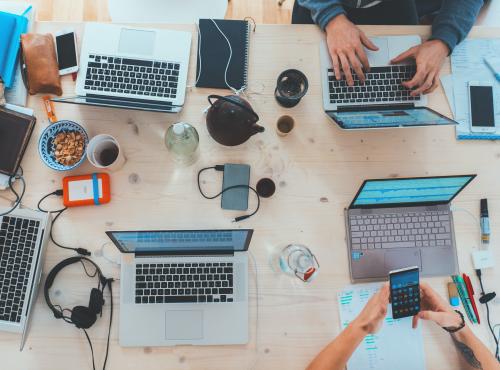 Image of people gathered around a table with laptops