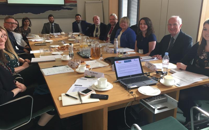 A photograph of the roundtable attendees sitting in a meeting room inside Portcullis House